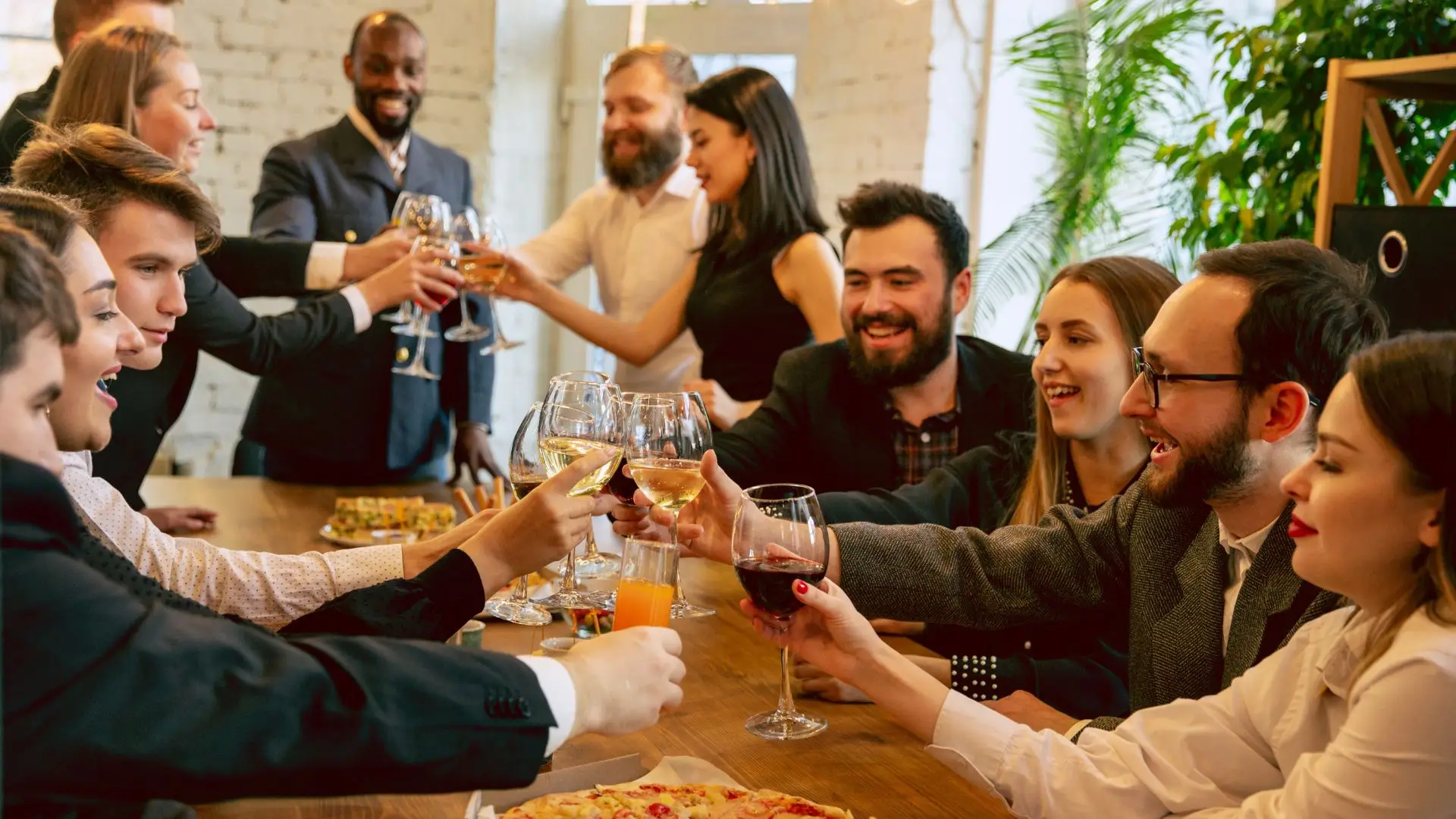 Group sharing a meal and raising glasses around a table